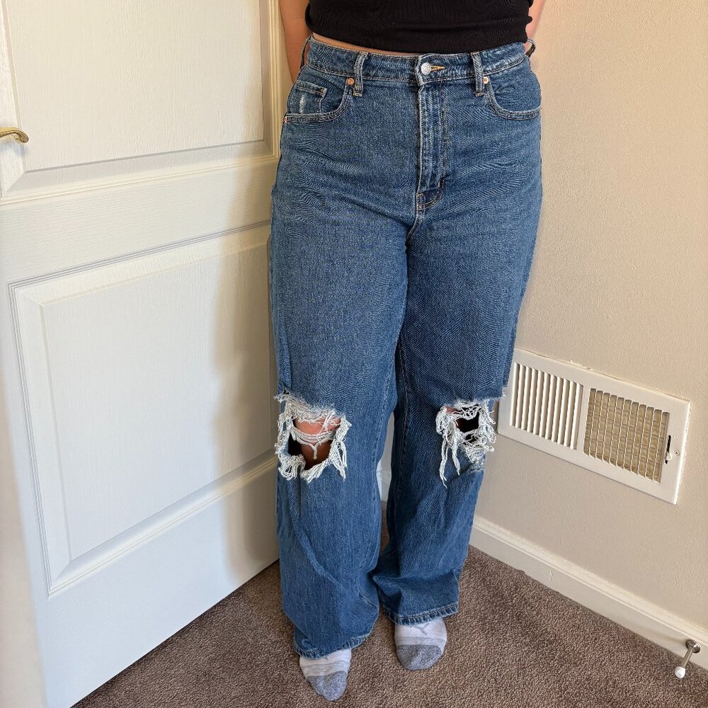 High-waisted, long, blue jeans with two holes on the knees